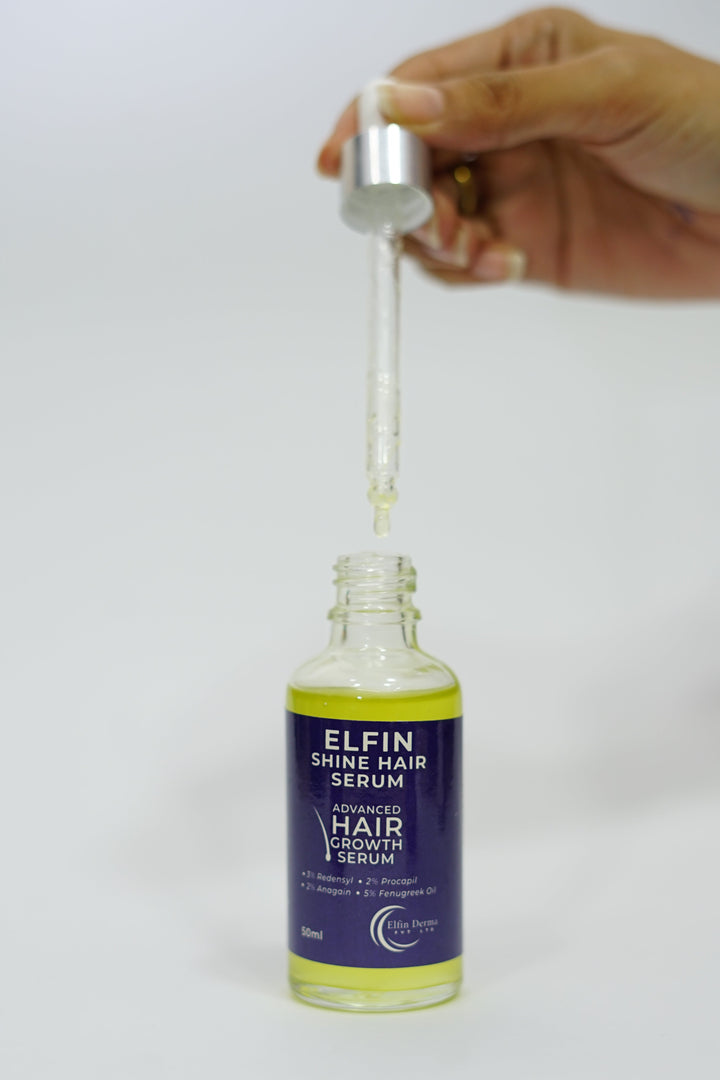 Hand holding a dropper over a Elfin shine hair syrum on a white background